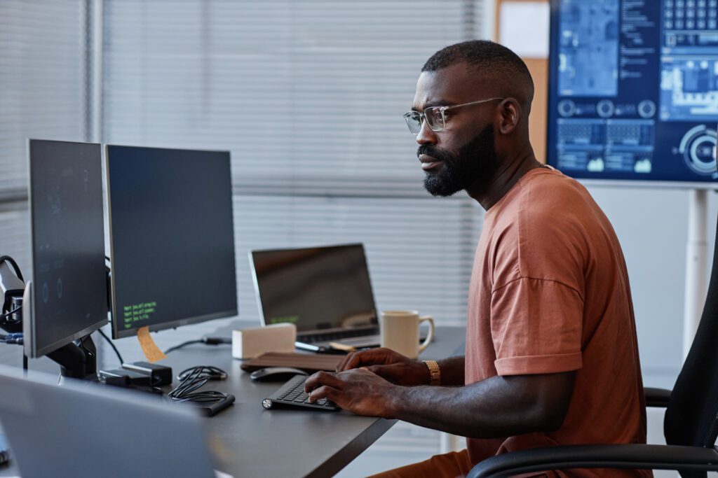 Man sitting in front of two computer screens working